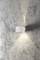 White wall lamp illuminates upwards and downwards on a textured grey background.