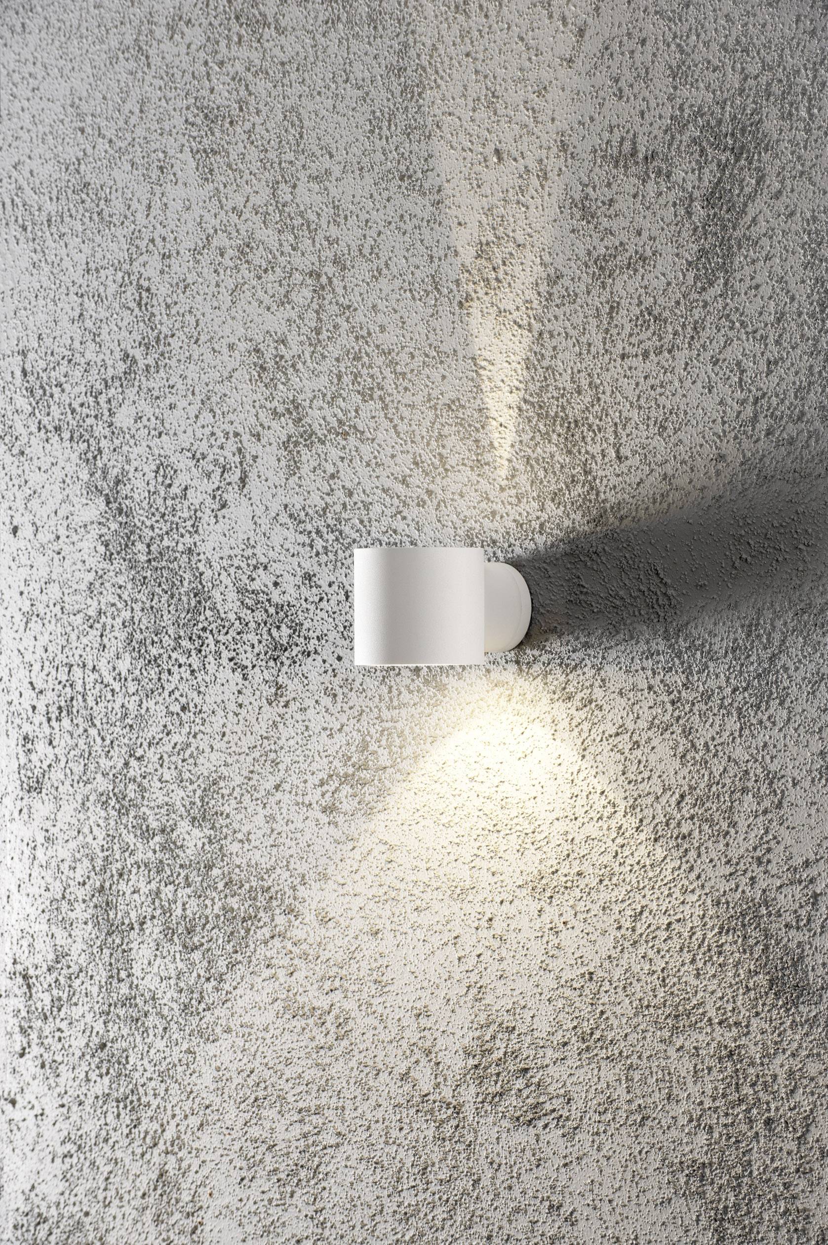 White wall light on a grey, textured surface, casting light upwards and downwards, creating a warm ambience.