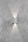 Wall light with a modern design that emits light upwards and downwards, mounted on a textured grey wall.