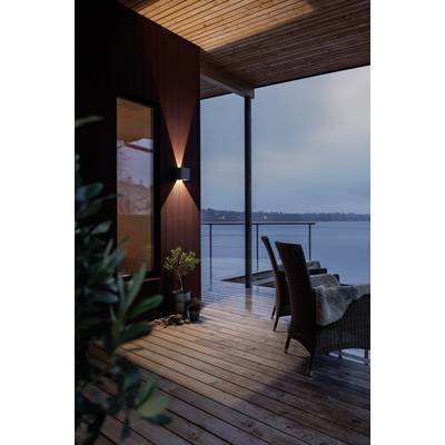 View of a covered terrace with wooden cladding, two wicker chairs, and a vista of a tranquil lake at dusk.
