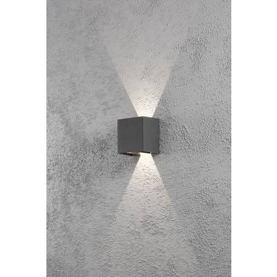 A grey wall light casts light upwards and downwards onto a textured wall surface.