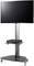 A large screen with a black frame is mounted on a silver stand. Below it, an electronic device sits on a shelf.