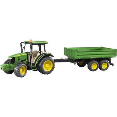 A green tractor with yellow wheels is pulling a green trailer. The tractor has a cab, and the trailer has three axles.