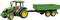 A green tractor with yellow wheels is pulling a green trailer. The tractor has a cab, and the trailer has three axles.