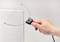 A hand holding an electric hot wire cutting tool is cutting into a white piece of foam.