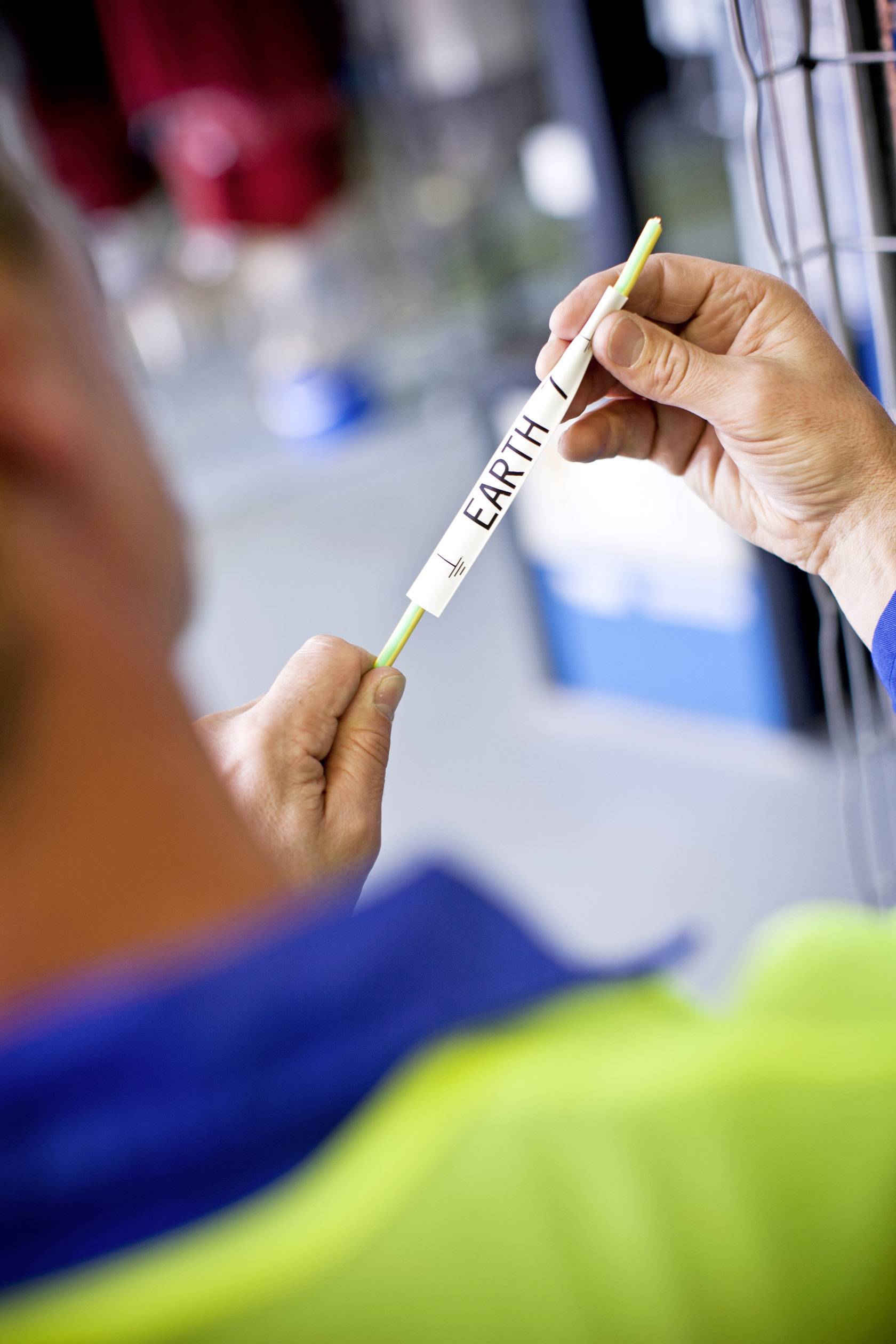 A person is holding a narrow white rod with the inscription 'EARTH' in an environment that looks like a laboratory.