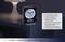 Black radio alarm clock with an analogue dial, digital alarm display and luminous hands. Functions: Snooze, silent buttons. Sits on a bedside table.