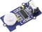 A PIR sensor on a blue circuit board, with various electronic components and connector pins, for motion detection.