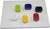 Six colourful, rectangular building blocks on a white baseplate, arranged in two rows. Colours: Green, Blue, Black, White, Yellow, Red.