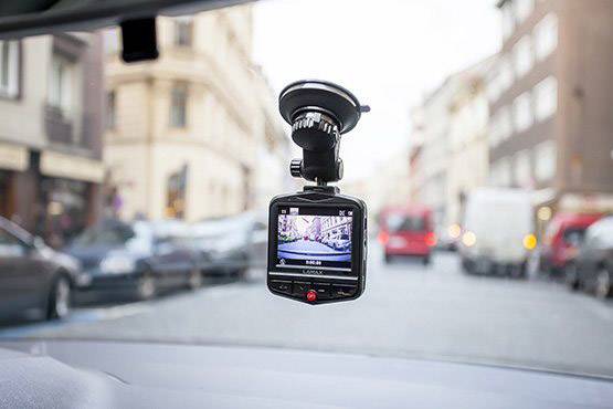 View through the windscreen of a car equipped with a dashboard camera recording road traffic.