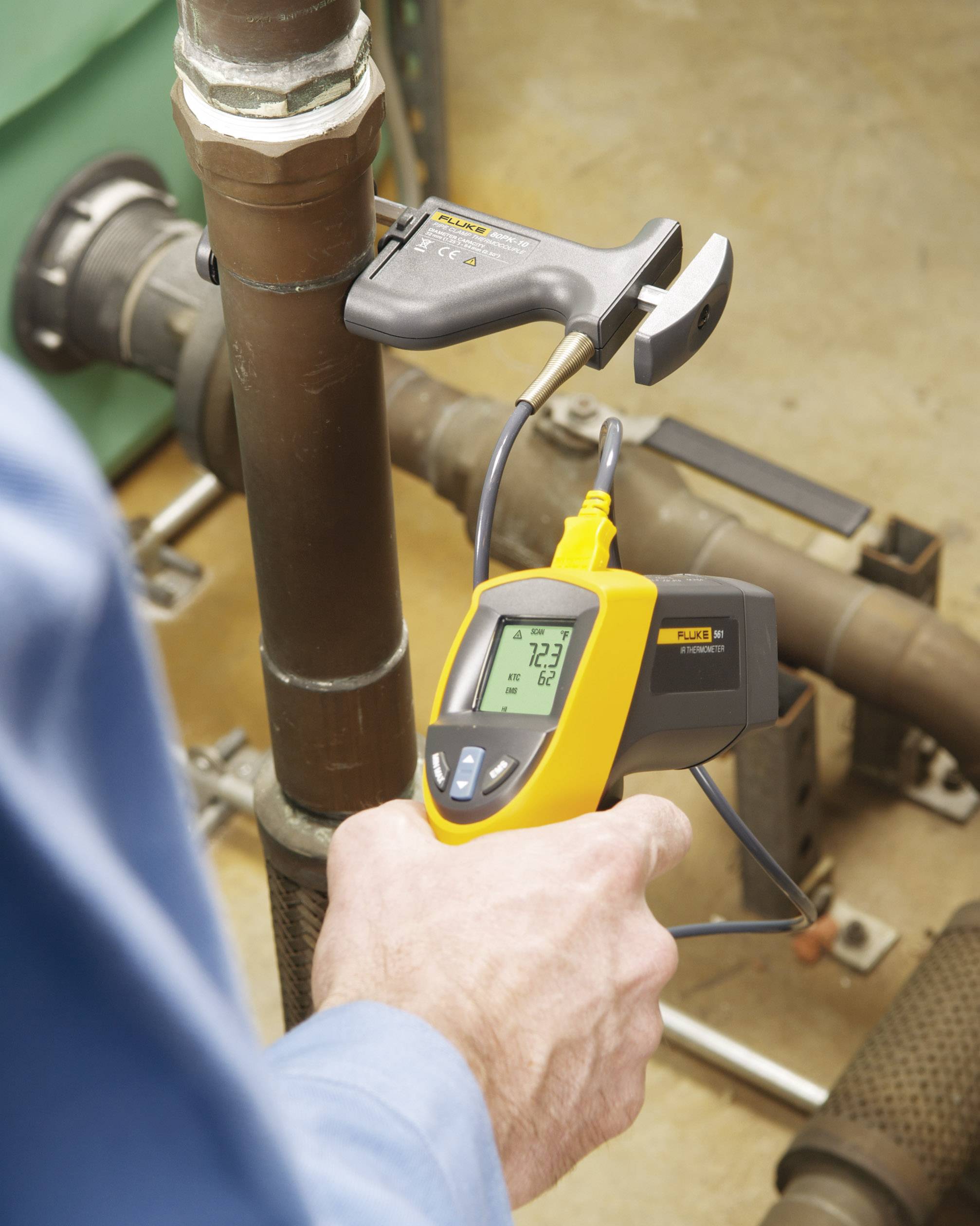 A person is measuring the temperature of a pipe with a digital thermometer. The display shows '72.7'. Pipe and tools are visible in the background.