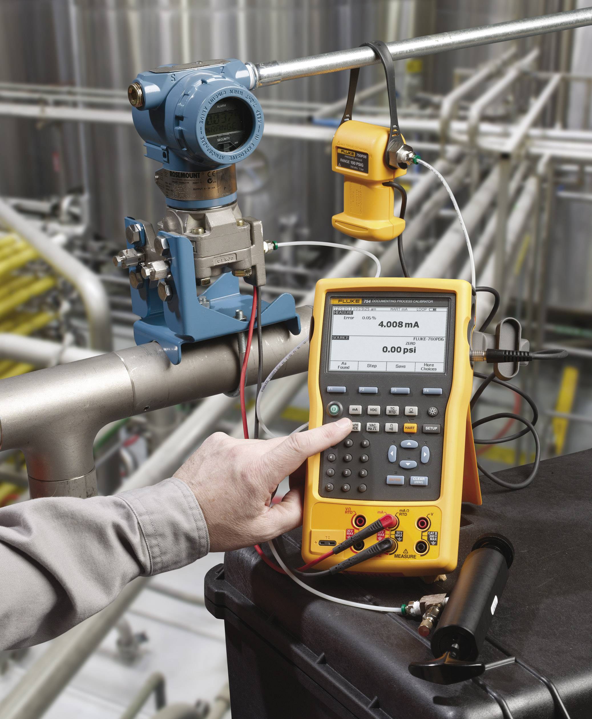 A person is calibrating a pressure measuring device with a multimeter in an industrial environment to ensure precision.