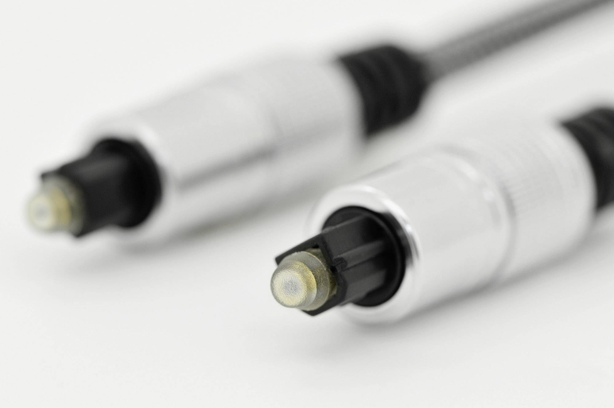 Two silver optical audio cables with black tips lie side by side. They are out of focus in the background.