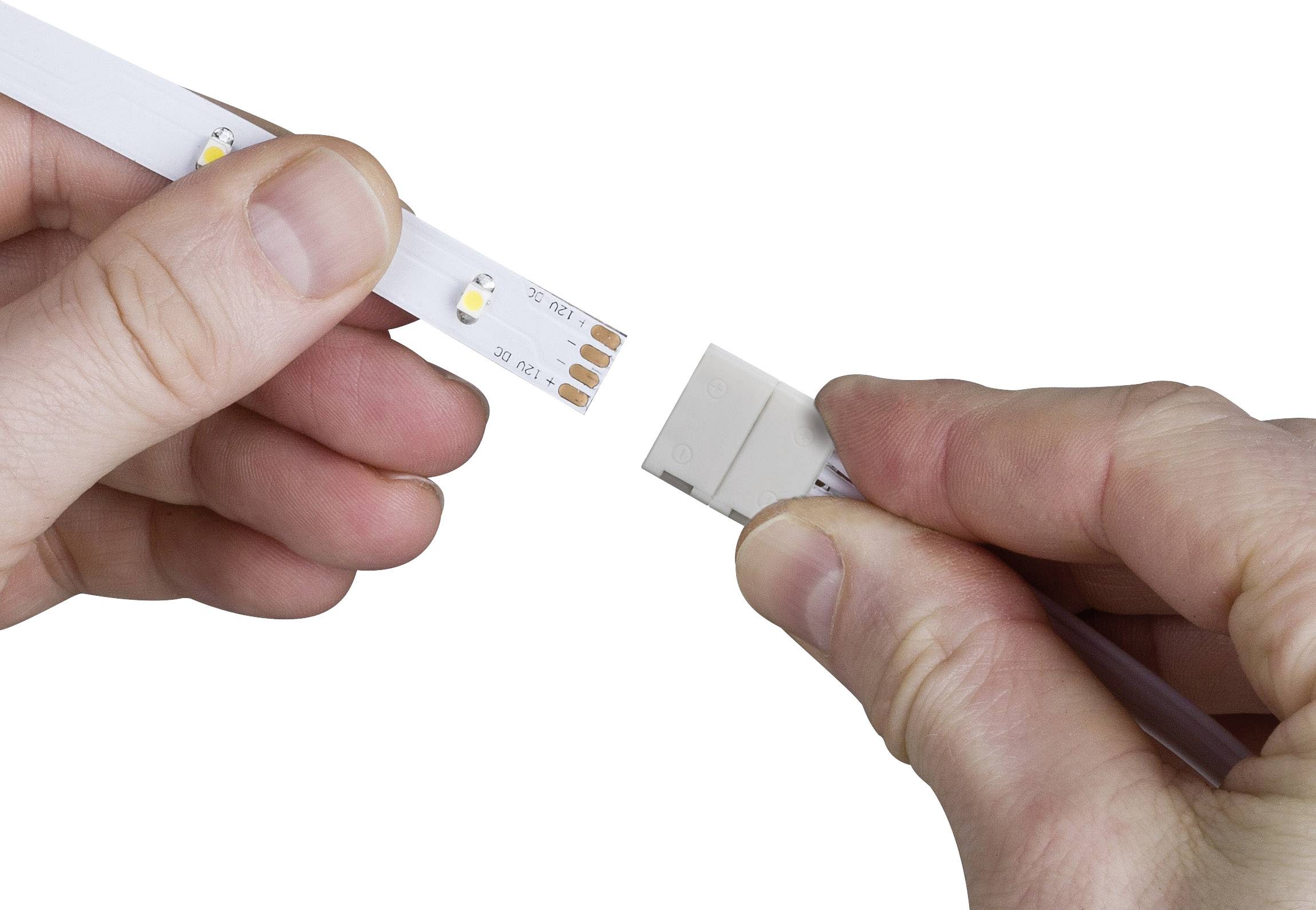 A person is holding an LED strip and an adapter. The strip is being plugged into the adapter to establish a connection.