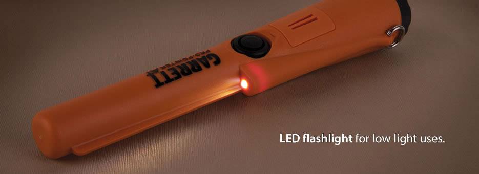 Orange LED torch by 'CARETT' for use in low-light conditions, resting on a brown surface.