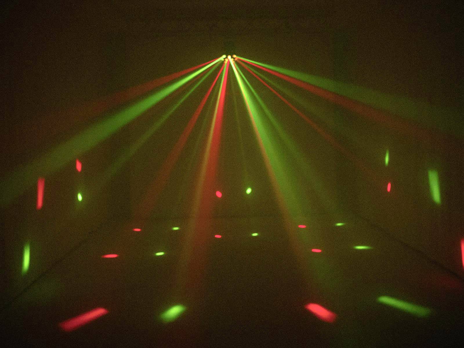 Red and green laser beams project a pattern of light points onto a dark surface, creating a dynamic, festive atmosphere.