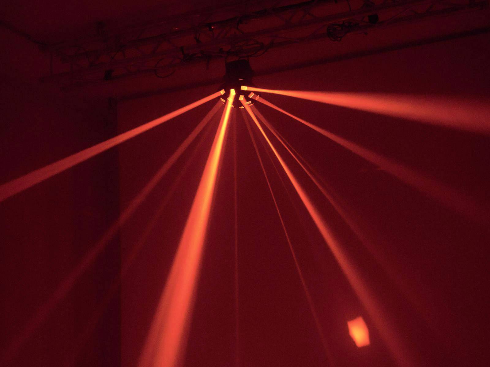 Red light beams radiate from a ceiling projector and illuminate the room.