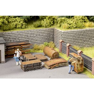 Model railway scene with workers moving old, rusty metal plates and a boiler in an industrial site.