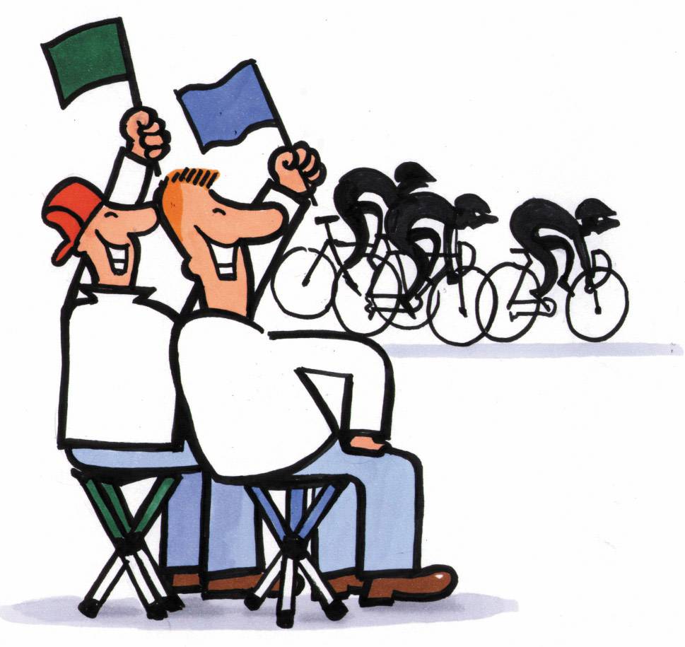 Two men wave flags as racing cyclists ride past during a competition. The scene depicts a cheerful atmosphere.