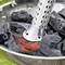 An electric fire starter heats charcoal in a metal bowl. The coal begins to glow and hot, red spots form.