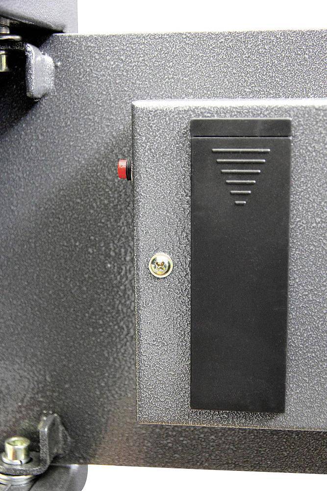 A black, rectangular plastic component is attached to a grey, metallic surface. Beside it is a red button.