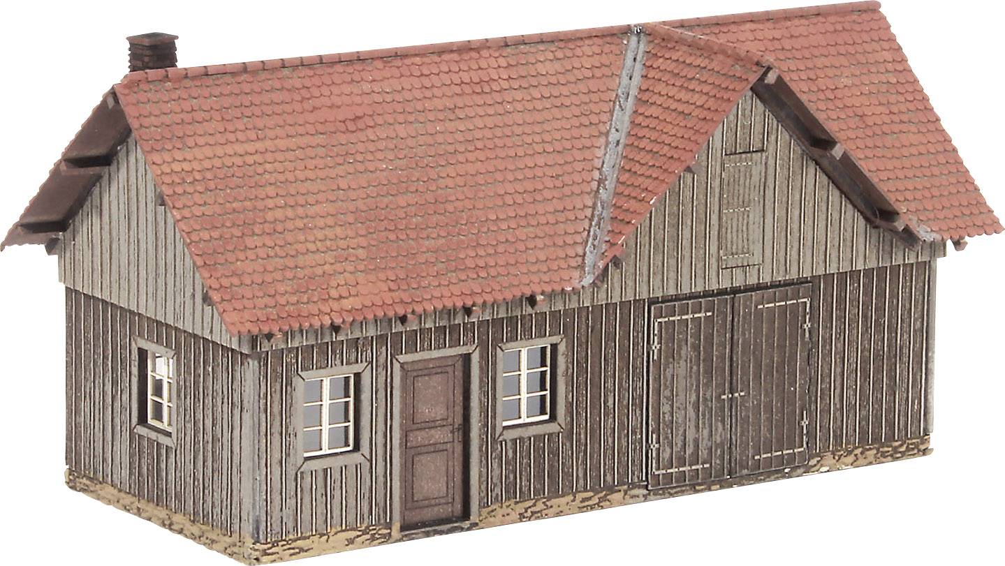 A small model house with a red tiled roof and wooden walls. It has windows and a door on the front, and looks rustic.