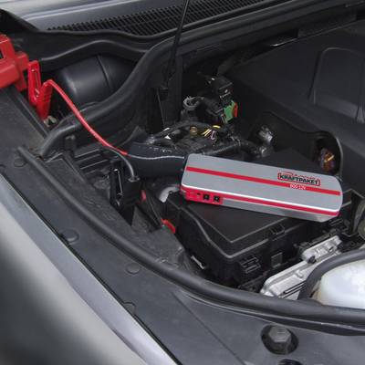 Engine compartment with a jump starter connected to the battery. The device is securely placed on the battery cover.