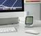 On a desk, a digital thermometer sits in front of a computer screen. It displays 12°C and 24% humidity.