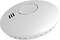Smoke detector on a white background, showing ventilation slots and a central button. Device for detecting smoke and fire.