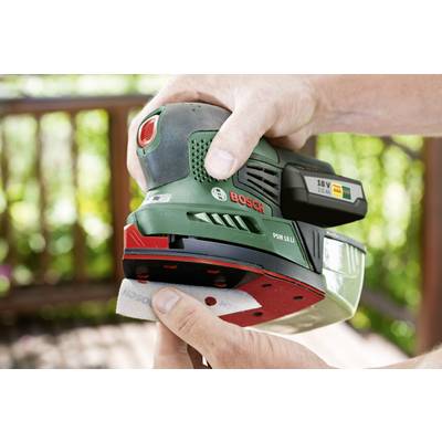 A person is holding a green Bosch cordless sander while changing sandpaper. Blurred wooden beams are visible in the background.