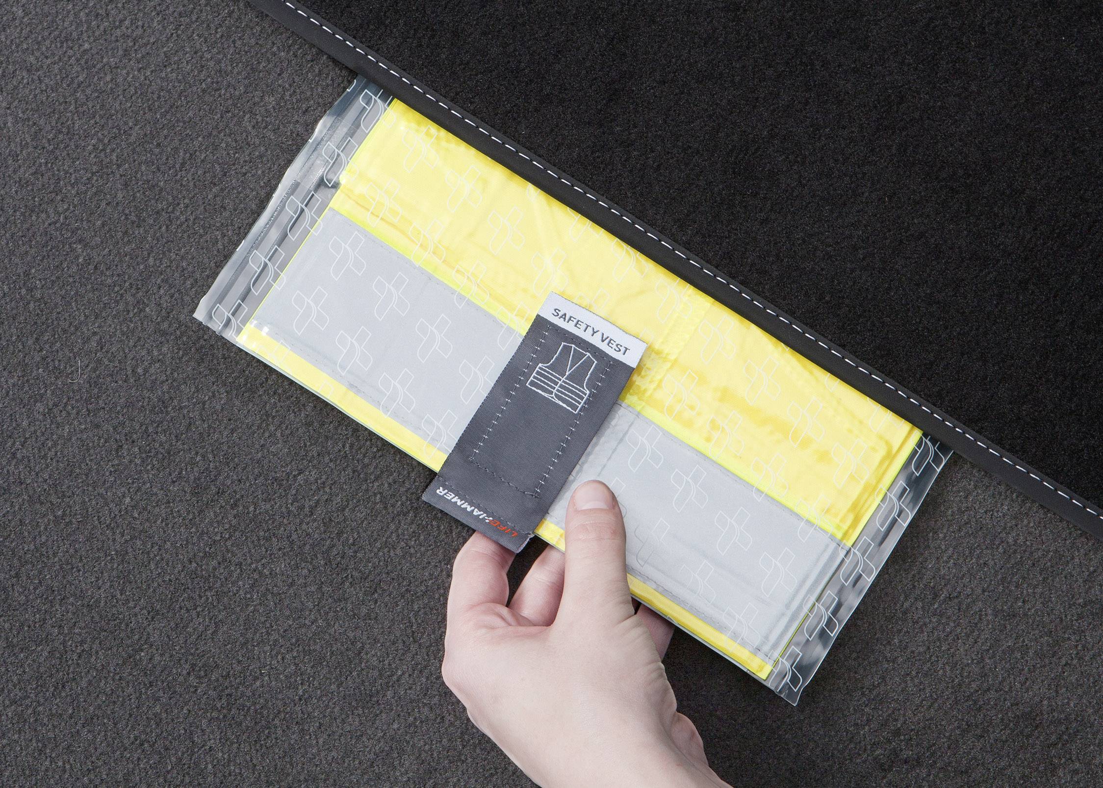 A person is taking a yellow high-visibility vest out of a black compartment.