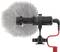 A shotgun microphone with a grey fur windscreen is attached to a red cable. It is suitable for clear audio recordings.