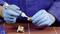 A person wearing blue gloves is applying adhesive to a metal thread in order to connect it with another component.