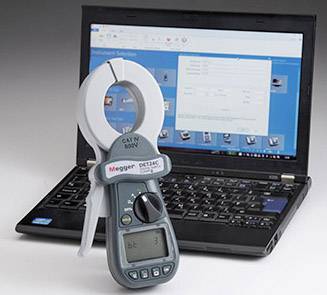 A clamp ammeter is placed in front of a laptop with an open screen displaying a technical software application.