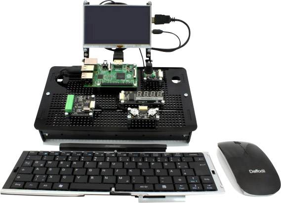 A Raspberry Pi kit with a screen, keyboard, and mouse. The Pi is mounted on a circuit board, connected to the screen above.