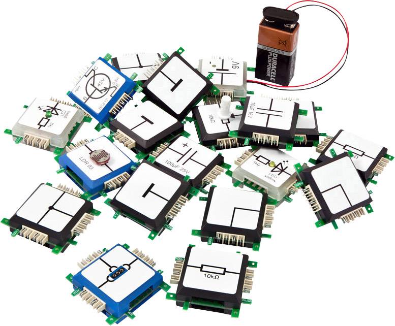 Several electronic component modules next to a 9V battery. Each module has different circuit diagrams and symbols printed on it.
