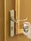 A hand sprays oil into the keyhole of a door with a golden door handle.