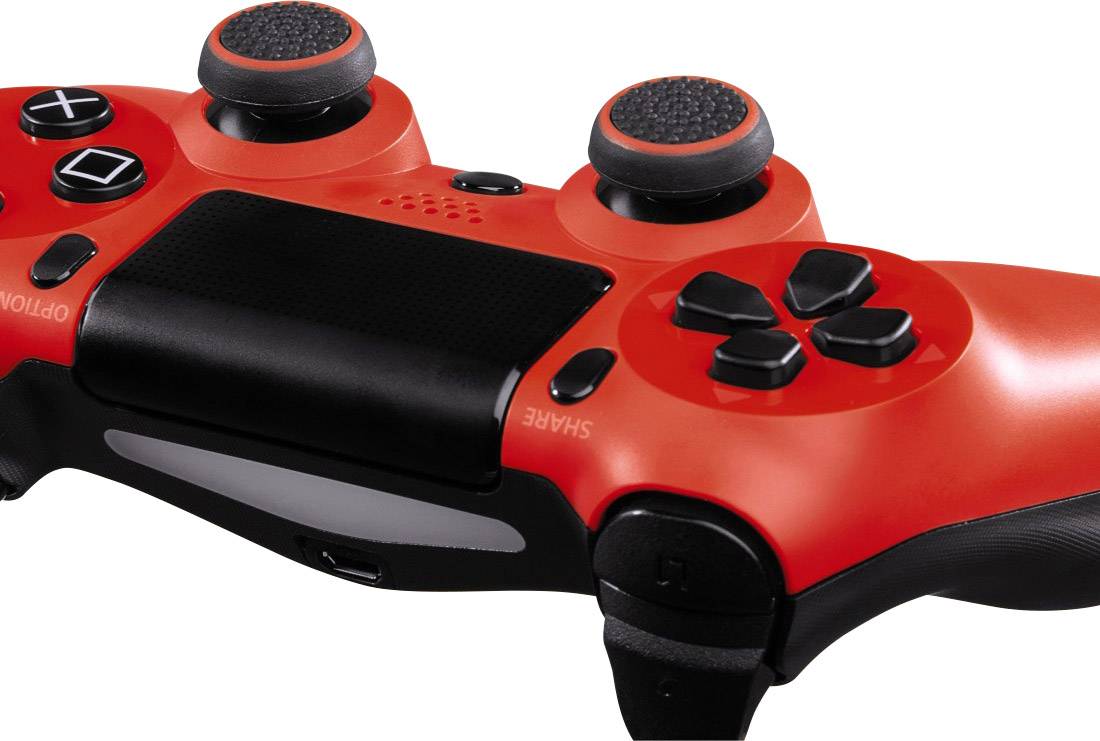 A red video game controller with black buttons and joysticks is lying on its side.