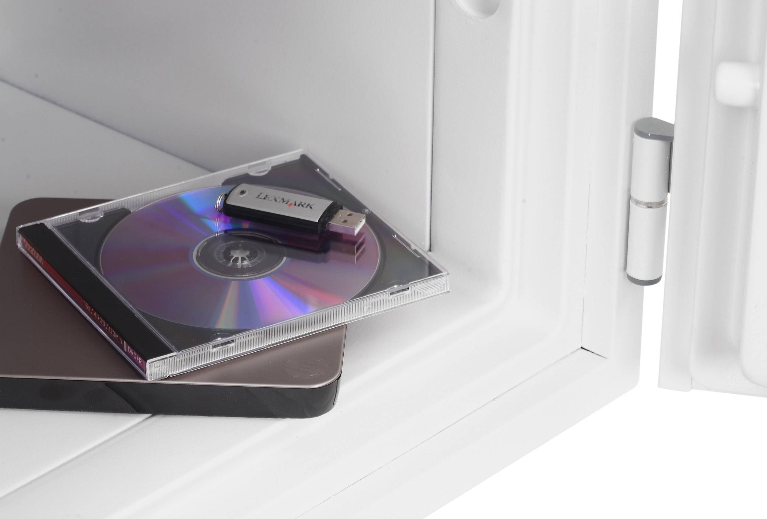 USB drive and CD in a case are lying in an open safe. A square-shaped object underneath, possibly an external hard drive.