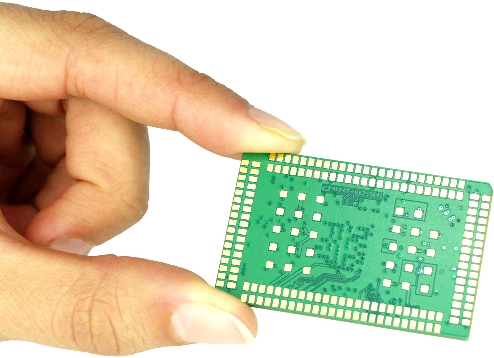 A hand is holding a green microchip with visible circuits and connections. The chip is small and rectangular.