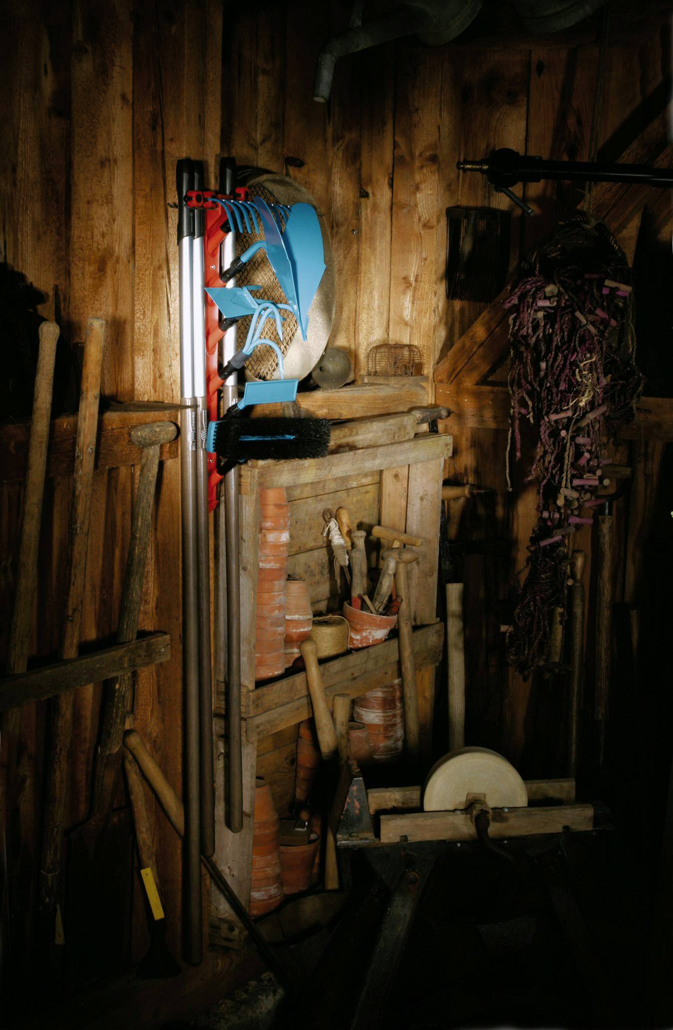 A shed with various tools, ceramics, a blue sculpture in the shape of an abstracted horse's head, and a grinding machine.