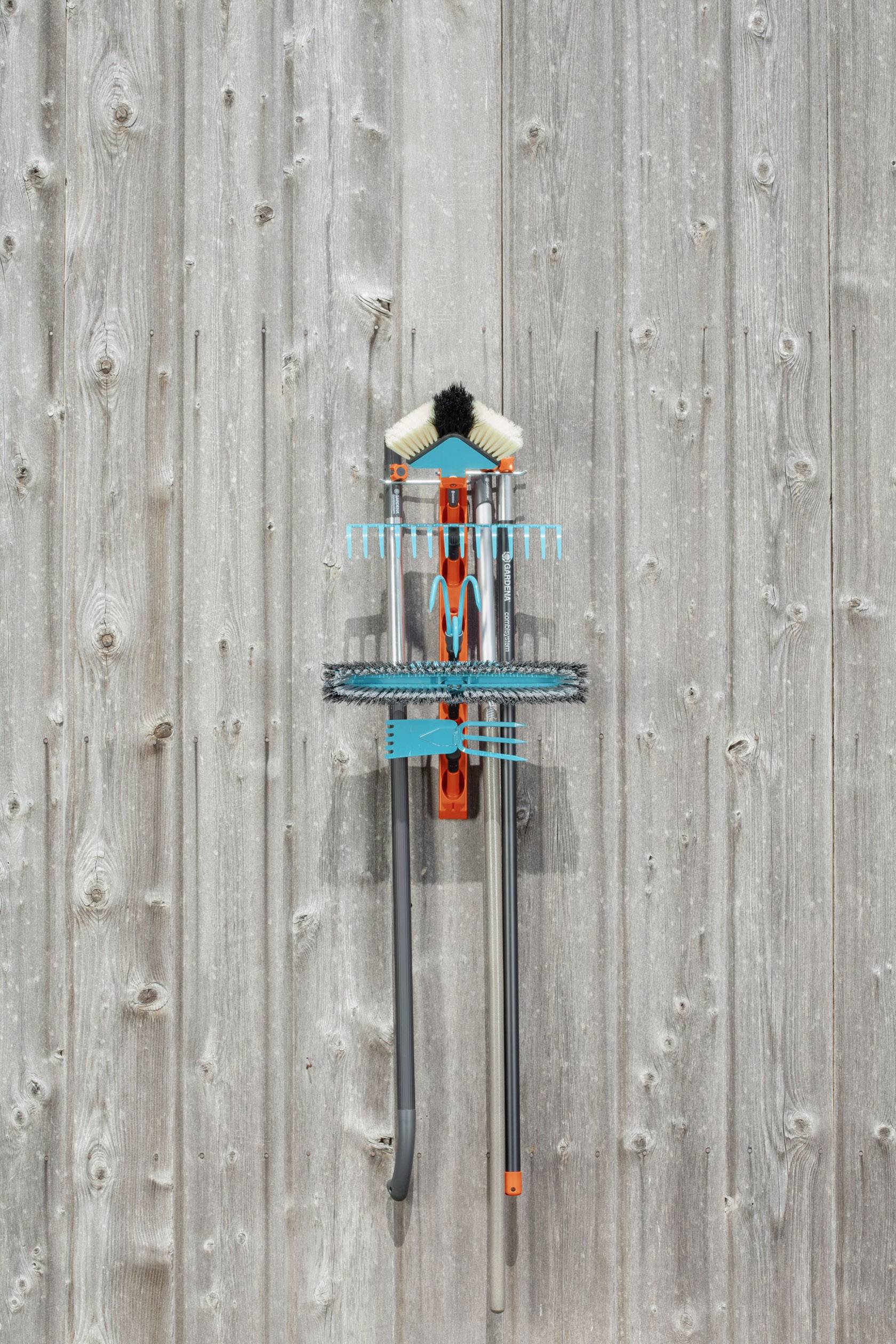 Colourful arrangement of cleaning brushes in the shape of a human figure, mounted on a wooden wall.