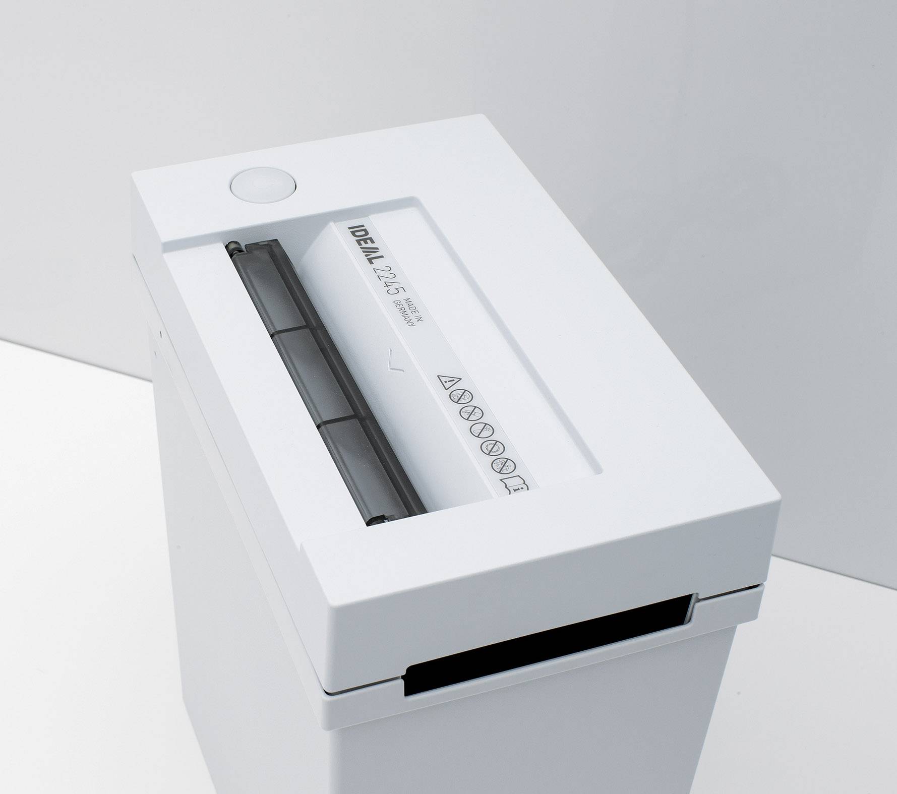 Paper shredder in operation: A sheet of paper is being pulled through the slot. The shredder has a simple, modern design.