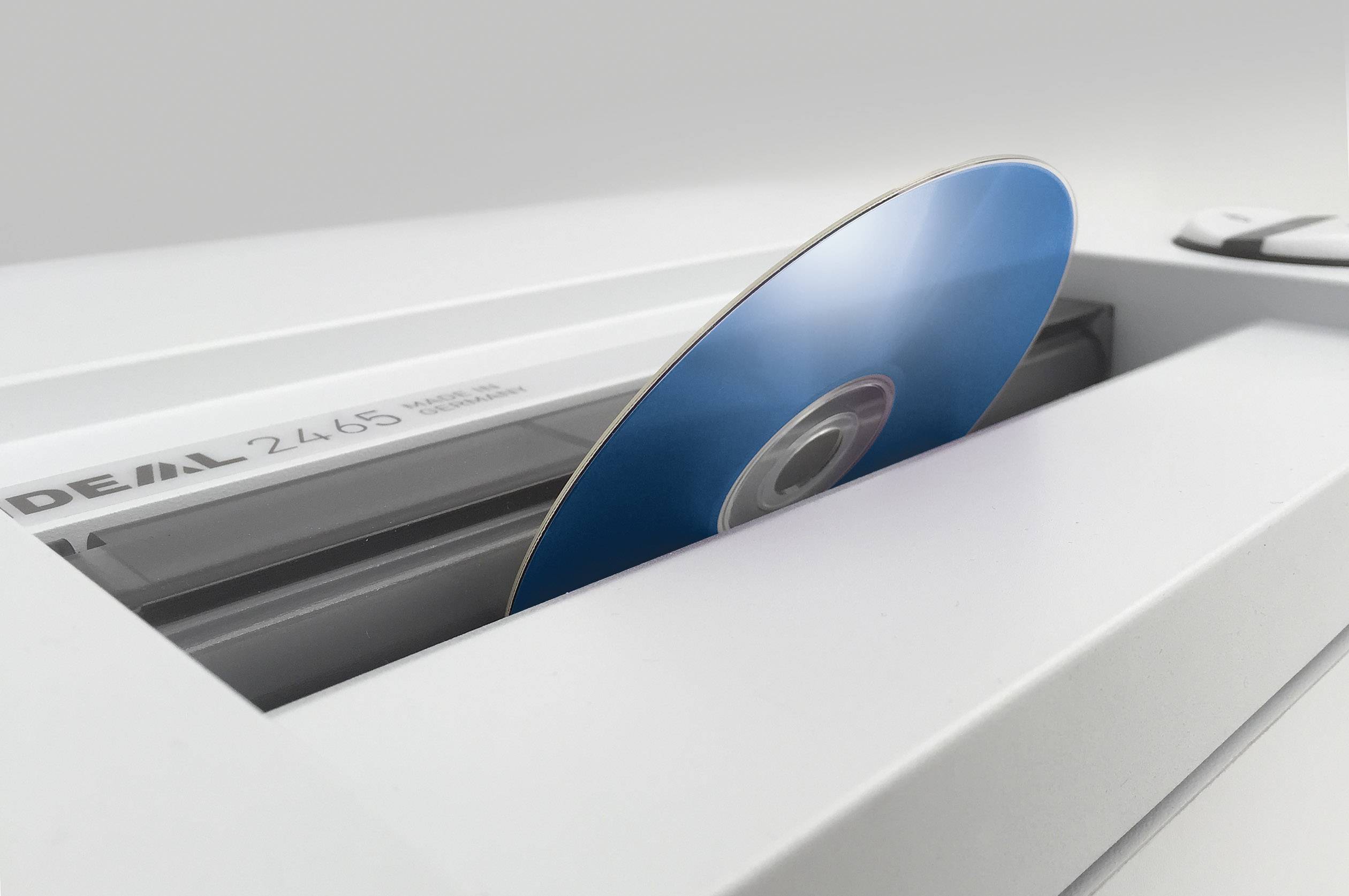 A blue data carrier is inserted into a paper shredder, which indicates the tearing up of CDs for secure data destruction.
