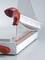 Paper cutting machine with a red handle and transparent protective cover. Cutting blade is secured in the resting position.