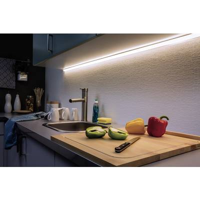 Kitchen with illuminated work surface. Chopped peppers are lying on the chopping board. Sink and crockery are visible in the background.
