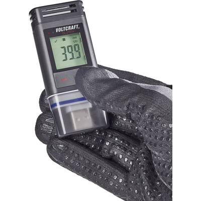 A hand wearing a black glove is holding a Voltcraft OL-230TH data logger. The display shows '39.0'. The device is used for temperature measurement.