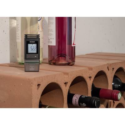 A hygrometer shows 52.2% humidity and is situated on a brick shelf with several wine bottles.