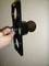 A hand holds a drill tool that is boring a round hole in a wall.