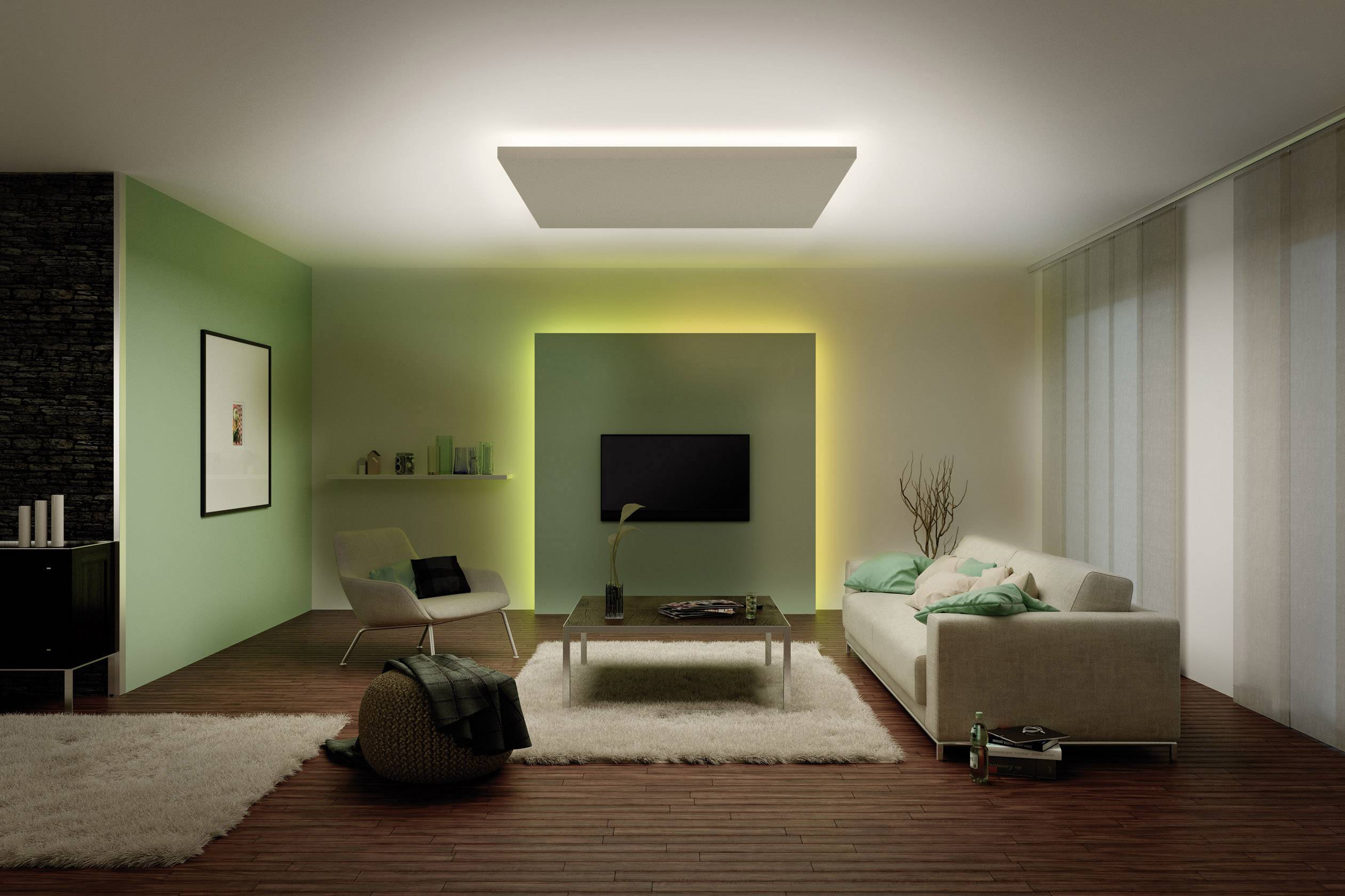 A modern living room with a sofa, coffee table, television mounted on the wall and stylish lamps. The walls are green and white.